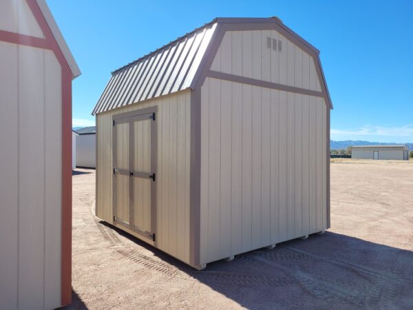 Barn style storage shed with tan walls and metal roof. Double doors, great for a garden shed or other storage uses.