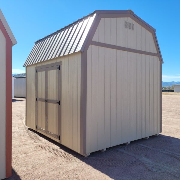 Barn style storage shed with tan walls and metal roof. Double doors, great for a garden shed or other storage uses.