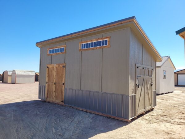 Large Royal Gorge style storage shed viewed from the front with double doors and ramp door on the side. Grey wooden walls with two wide short windows at the top.