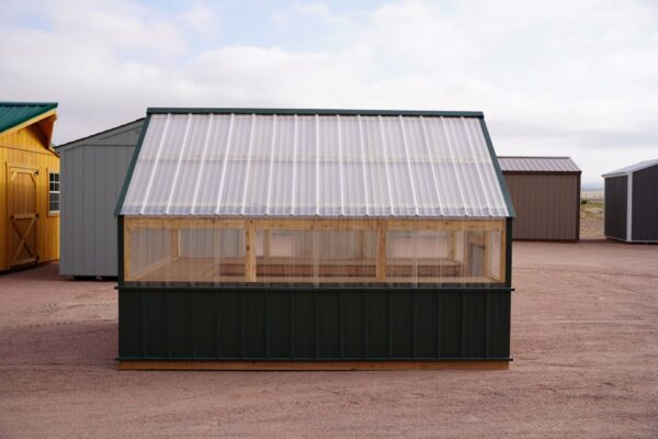 Side view of an 8x12 Green House with wood frame, green metal siding and roof, and plastic covering on the upper walls.
