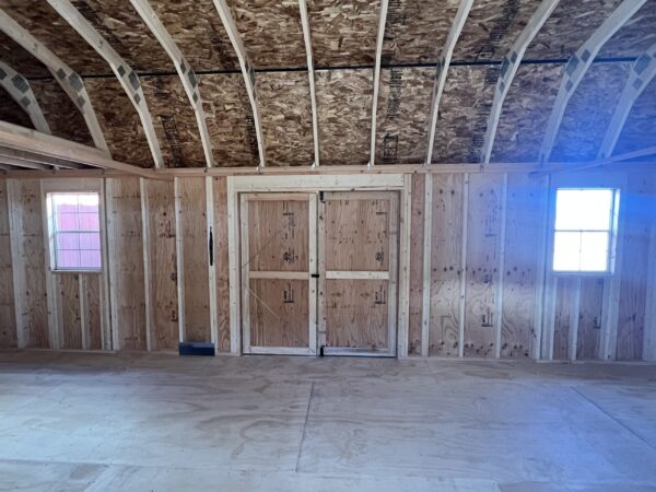 Step into the expansive interior of our 14x32 Barn Style storage shed and behold the picturesque view of the double doors flanked by windows on both sides. Sunlight streams through the windows, creating a bright and inviting atmosphere within the spacious storage area. This delightful combination of natural light and thoughtful design ensures a pleasant and well-lit environment for all your storage needs.