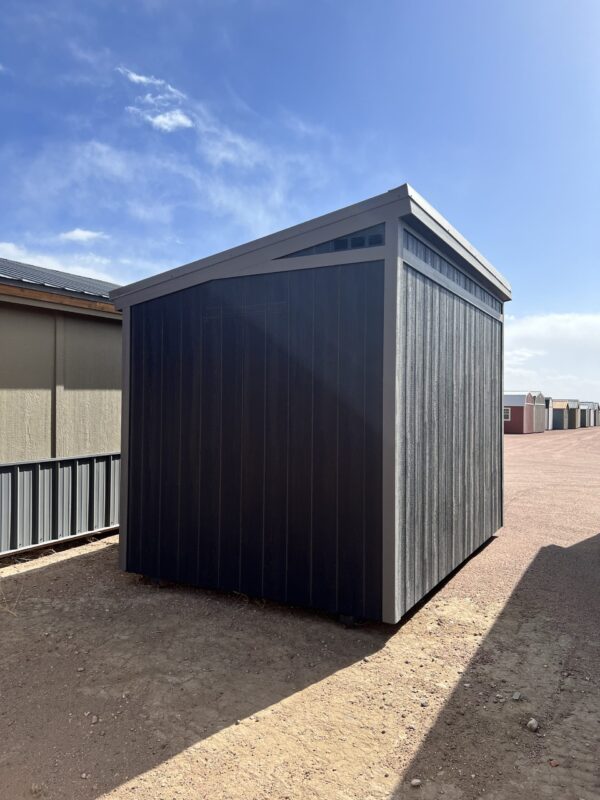 A view of the back side of the 8x12 Urban Style storage shed, showing the angled roof and wood paneling on the walls.