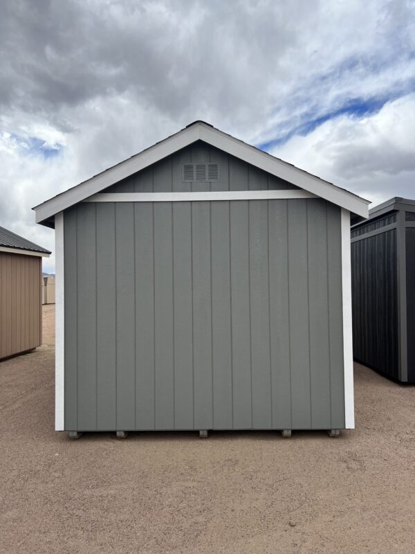 The sky is filled with clouds as a 10x20 Gable Style shed stands on the outdoor property, viewed from the back.