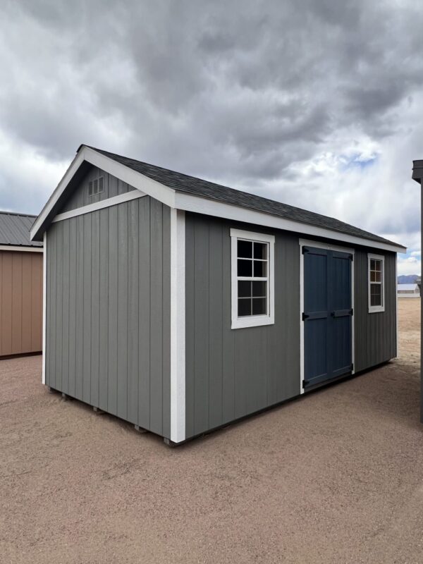 A view from the front corner of a 10x20 Gable Style storage shed with grey walls and big blue-grey swinging doors.