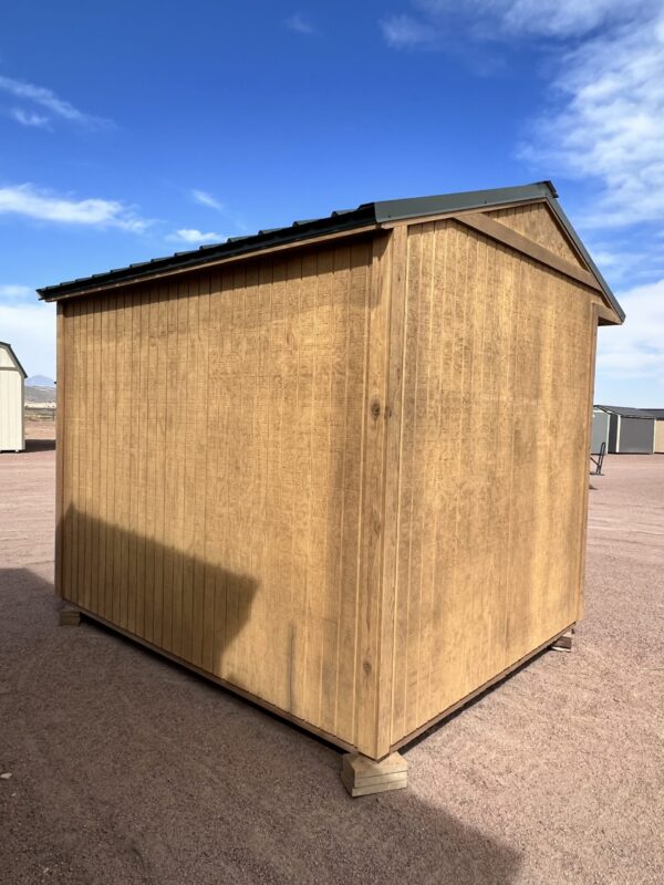 Experience the versatility of our 8x10 Loafing storage shed as you observe it from the right back corner, showcasing its sturdy brown wooden paneling, a striking green roof with an ample overhang, and the perfect blend of durability and aesthetic appeal.