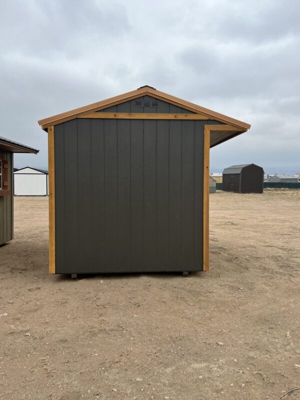 A wooden sentry box stands on a sandy beach coast, surrounded by a cloud-filled sky and an outdoor waste container.