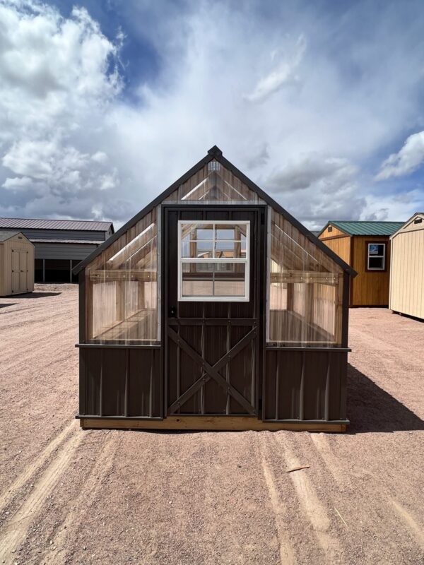 A view of the 8x8 Greenhouse, showing the large door in the front. In the background are several other storage sheds.